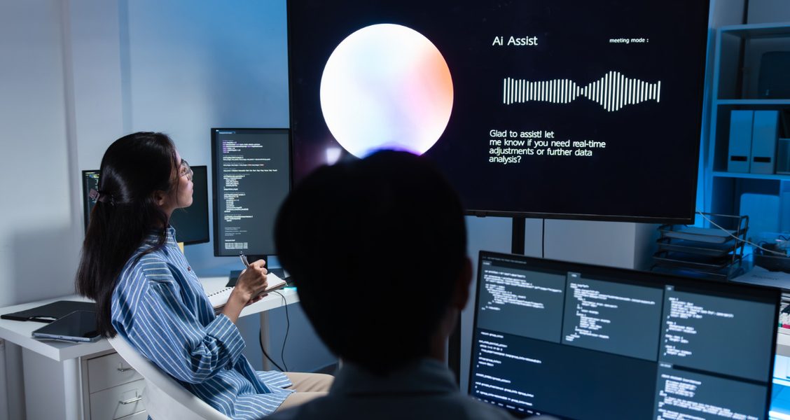 Two colleagues reviewing AI-generated suggestions on a large meeting-room screen