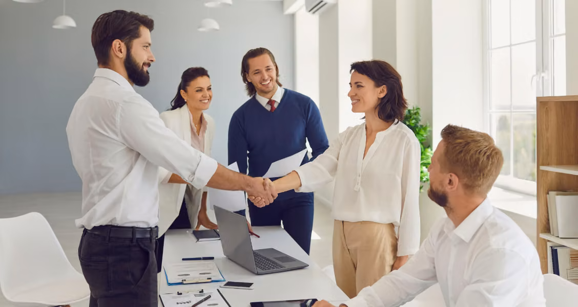 Team welcoming a new client with a handshake at the start of onboarding