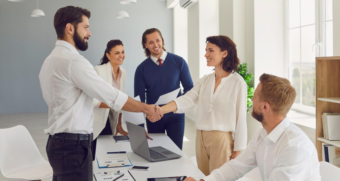Team welcoming a new client with a handshake at the start of onboarding