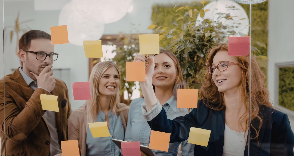 Comms team maps an internal communications plan with sticky notes on a glass wall