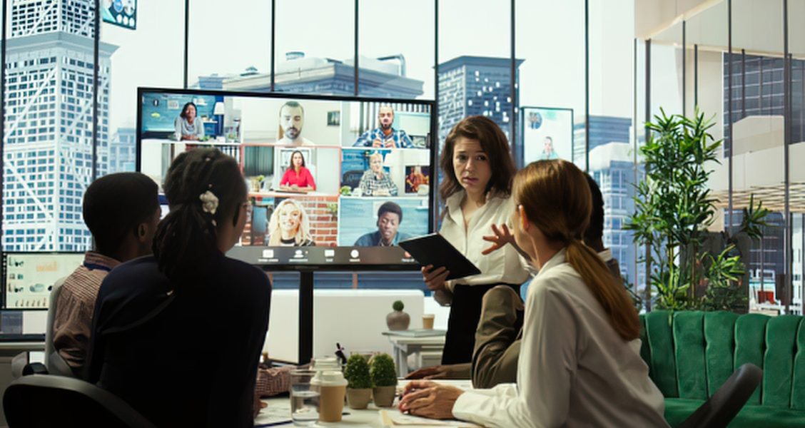 Office team holds a hybrid meeting with remote colleagues on a video wall, one of the internal communications tools