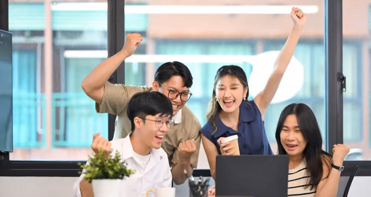 Proposal team cheers at a laptop after a win, the outcome that proposal and RFP statistics track