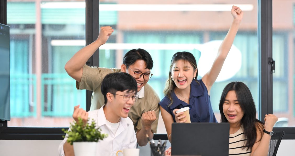 Proposal team cheers at a laptop after a win, the outcome that proposal and RFP statistics track