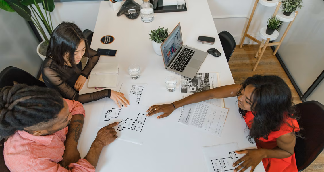 Talent team discussing a campaign plan and printed documents around an office table