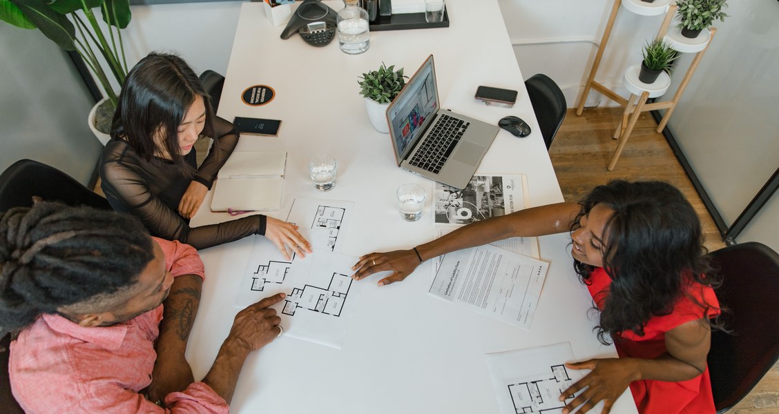 Talent team discussing a campaign plan and printed documents around an office table