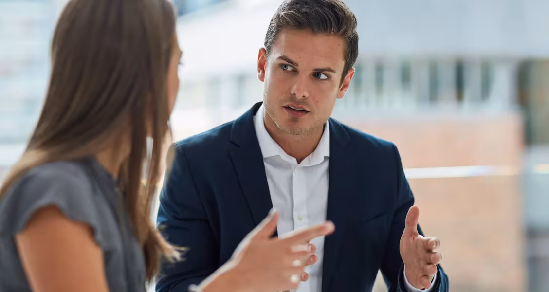 Two sales professionals in a calm, collaborative conversation raising and addressing a concern
