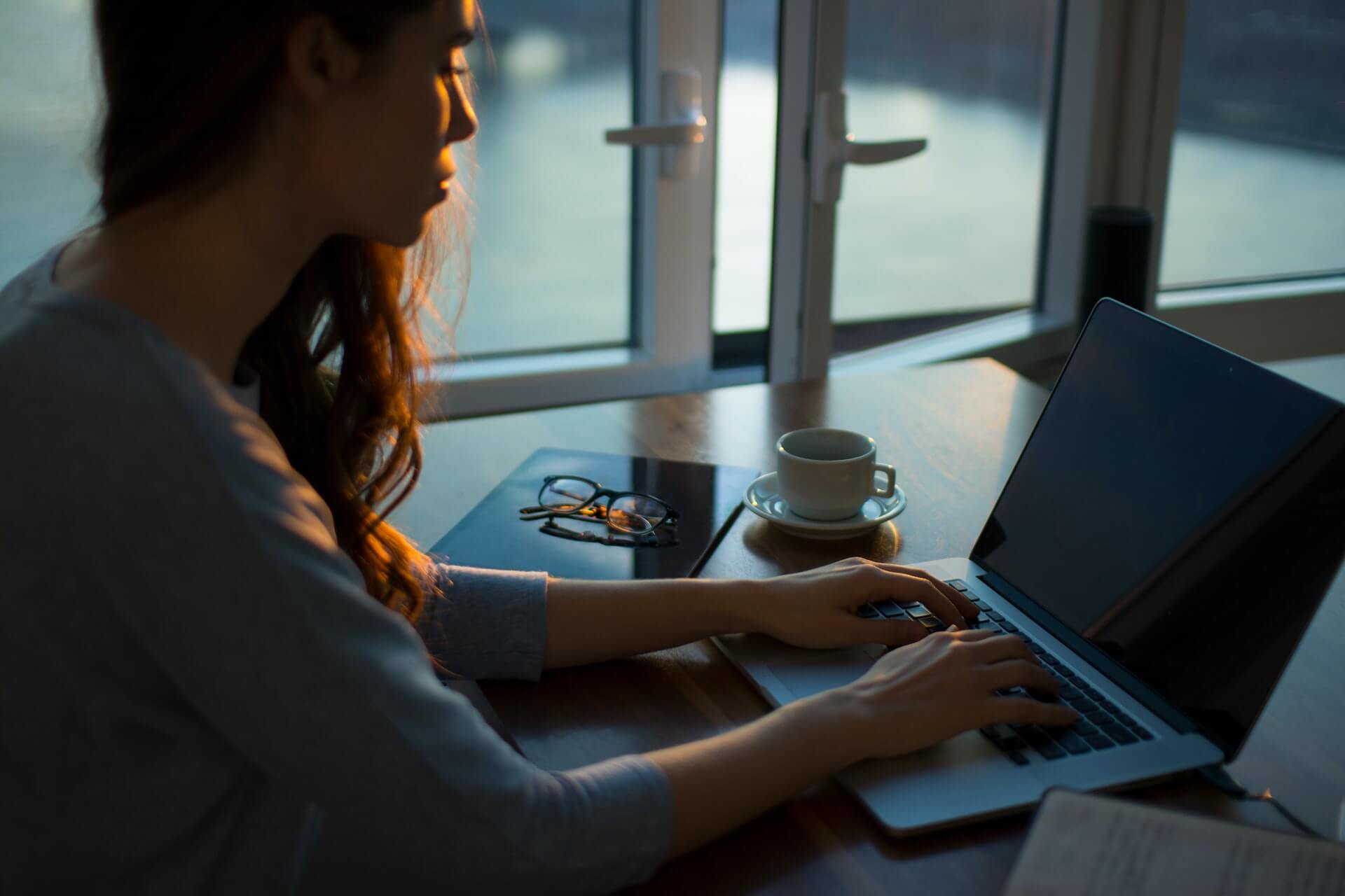 Woman sitting at a desk typing on a laptop.