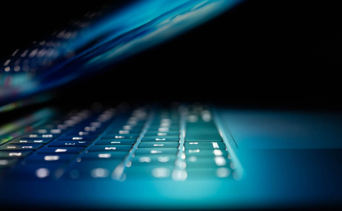 A close-up of a laptop keyboard with the lid half open.