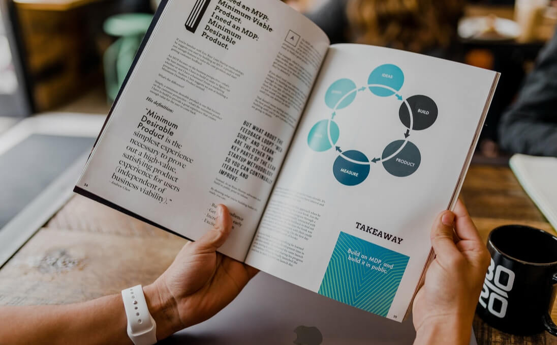 Pair of hands holding a book, which has information about minimum desirable product.