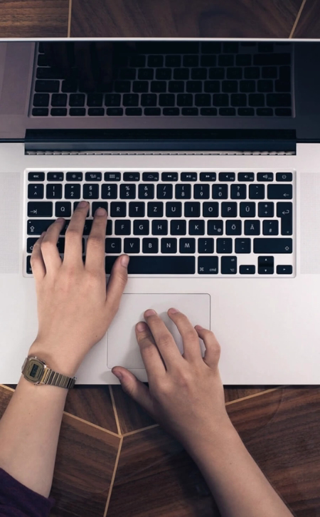 A pair of hands typing on a laptop.