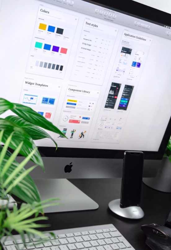 A monitor, a keyboard and a mobile phone on a desk.