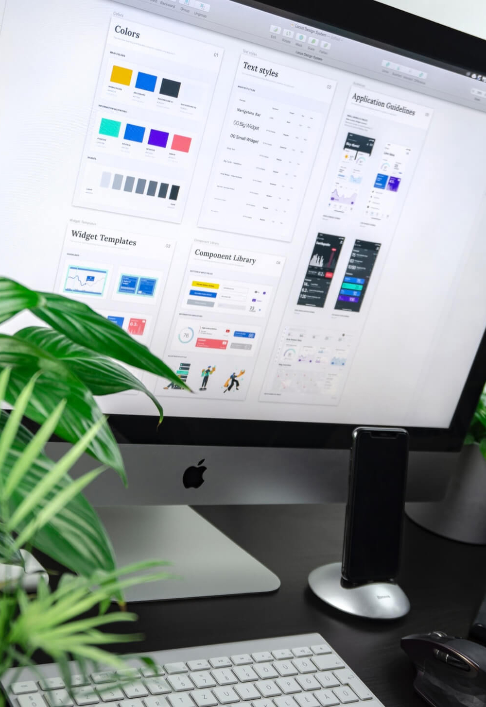 A monitor, a keyboard and a mobile phone on a desk.