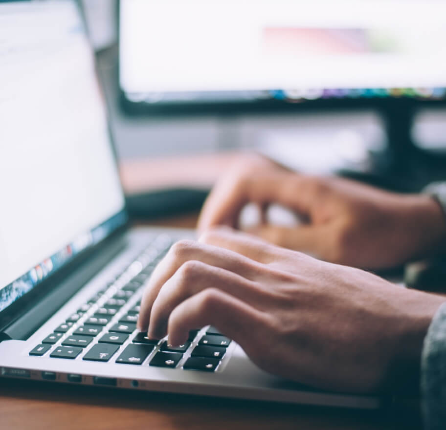 A pair of hands typing on a laptop.