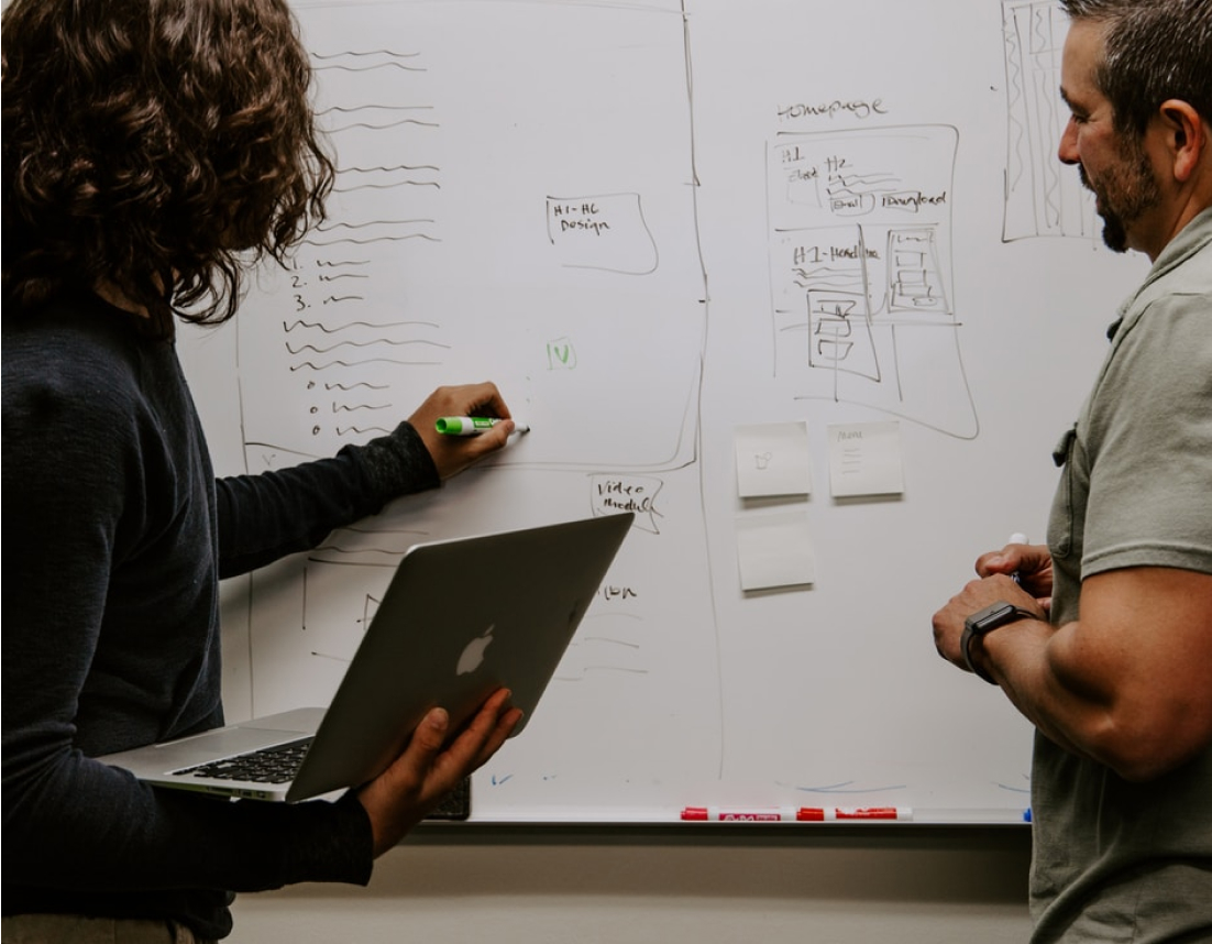 Two people designing a webpage on a whiteboard
