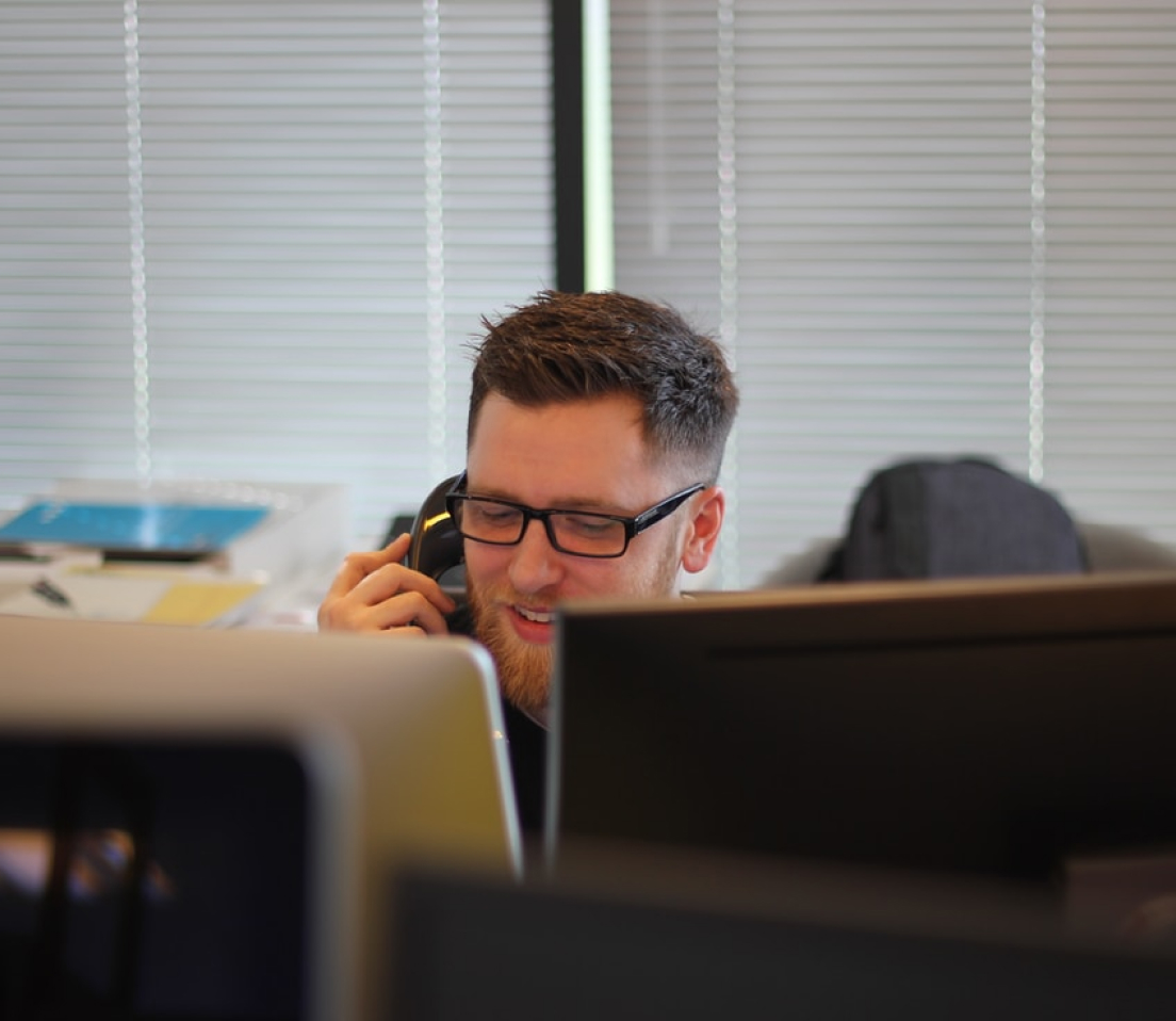 A man sitting at a desk talking on a telephone.
