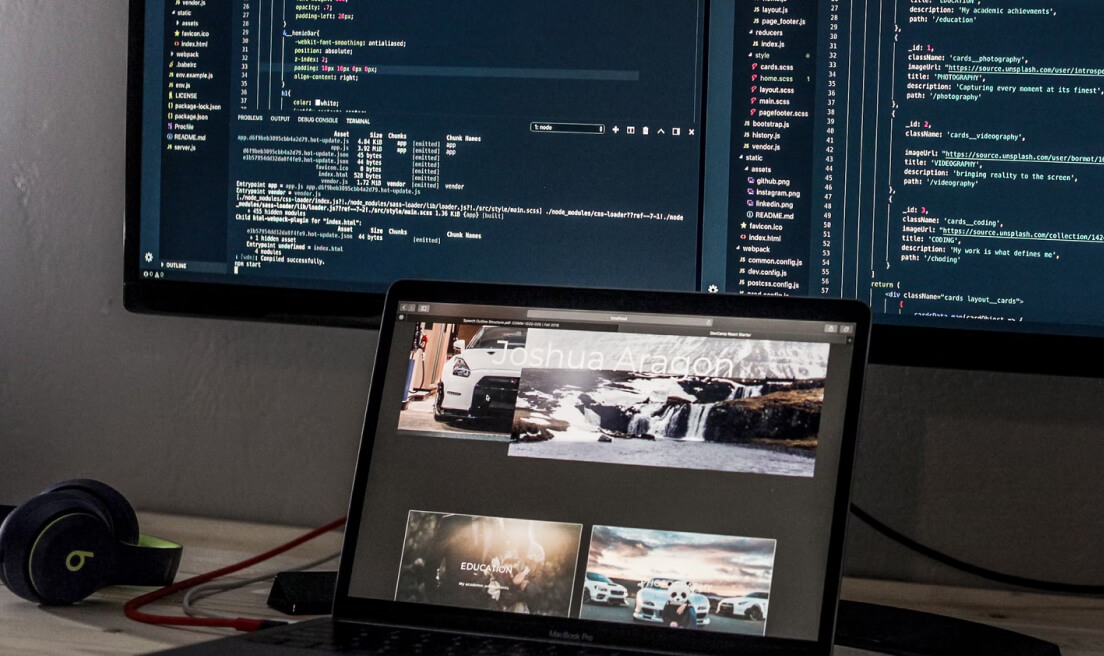 Desk setup with a laptop and two large monitor screens.